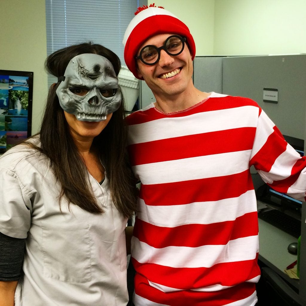 two people dressed up for Halloween - a woman with a skull mask and a man dressed up as Where's Waldo